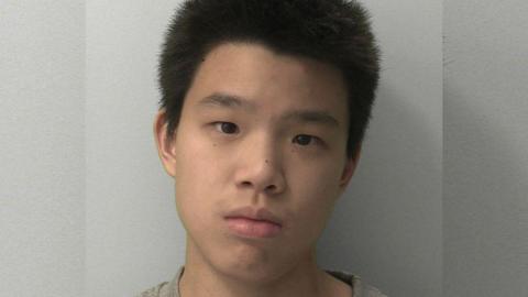 A mugshot of a boy with short black hair looking expressionless.