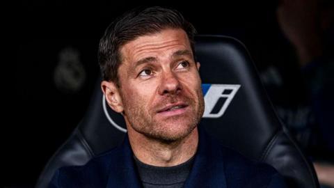 Xabi Alonso smiling while sat in the Real Madrid dugout