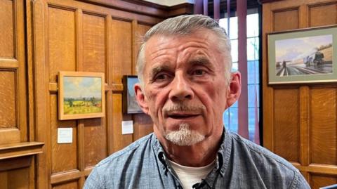 A man in a blue shirt stood in an art gallery