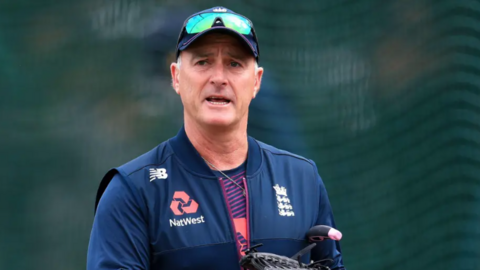 An image of former England and Surrey cricketer Graham Thorpe. He is wearing a new balance gilet with England and Natwest emblems. He is wearing a cap and sunglasses.