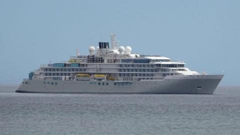 A large cruise ship sits on a still sea.