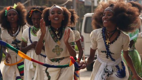 Orthodox Christian women clap as they walk down in traditional white outfits with silver cross necklaces in Mekelle in Ethiopia - archive shot