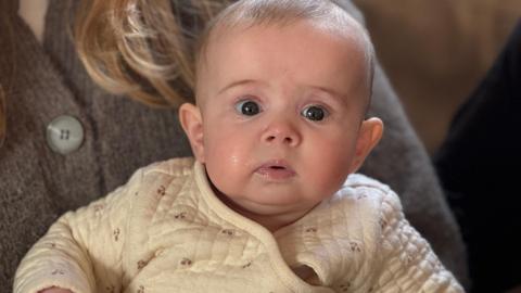 A baby in a cream jacket