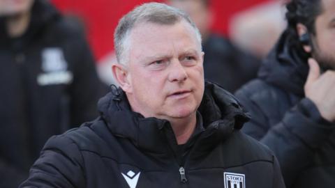 Stoke City boss Mark Robins walks towards the changing room after a game