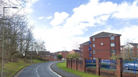 A bend in Navigation Way with trees on the right and a small block of flats on the right