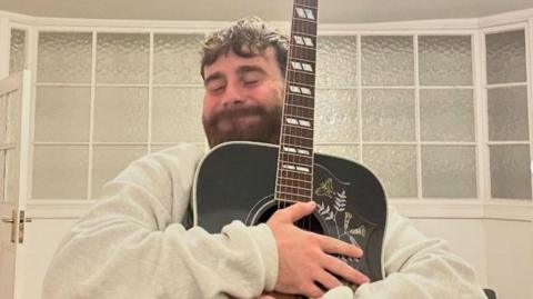 Sam Tompkins with his Gibson acoustic guitar