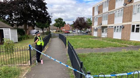A police officer guarding a cordon outside a block of flats.