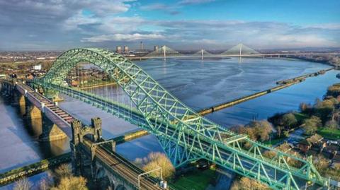 Aerial image of the Silver Jubilee Bridge which crosses the River Mersey and the Manchester Ship Canal at Runcorn Gap between Runcorn and Widnes