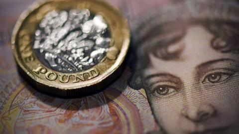 Close-up shot of a pound coin and a note.