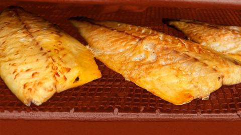 Racks of fish fillets inside a smoke.