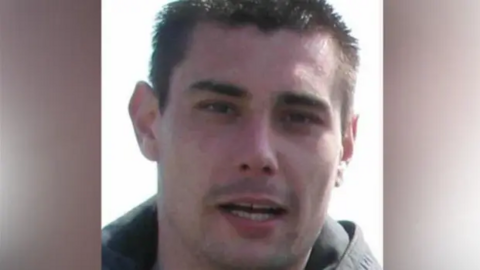 Ricky Crosher is pictured looking at the camera. He has short spiky dark hair