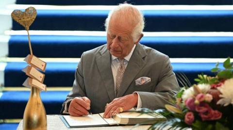 King Charles signing condolence book