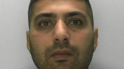 A man is staring at the camera in a police mugshot.