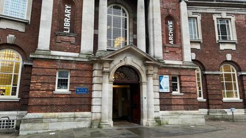 York Explore's main entrance in Library Square. The building is made of red brick and features two pillars above the entrance.