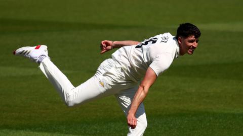 Matt Fisher bowling for Surrey in his follow-through
