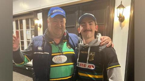 Chris Sansome and Matthew Sansome stand side by side with their arms over each other's shoulders. Both are wearing Northampton Saints jerseys.