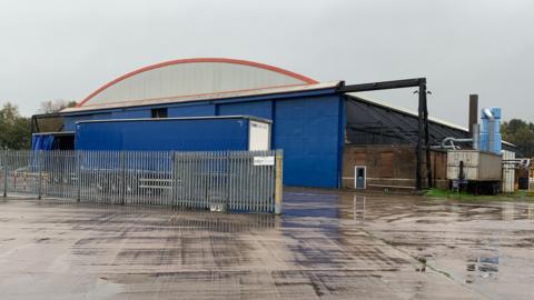 A blue industrial building with a lorry parked outside on a dreich Scottish afternoon