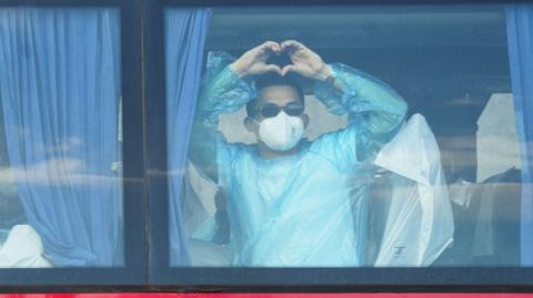 A person makes a heart shape with his hands while riding a bus transporting passengers from the MV Hondius cruise ship to Tenerife South Airport from the Port of Granadilla de Abona in Tenerife, Spain, 11 May 2026.
