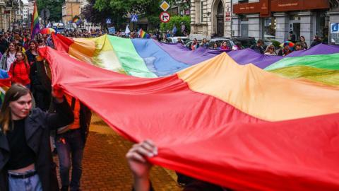 Participants of an equality march in Poland hold an LGBTQ flag in Krakow