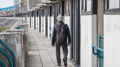 An unidentified man walking on the crescent walkway of Alexandra Road estate in London, UK
