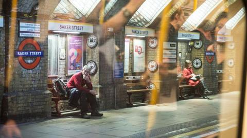 Commuters sit on the Baker Street Station platform