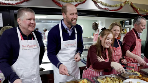 Prince William, pictured in a The Passage branded apron, stands in a line with other volunteers as he dishes out carrots and parsnips 