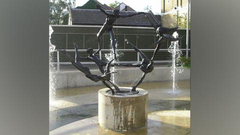 The statue shows five nude people in metal holding a limb of one another in an acrobatic pose with water shooting around them.