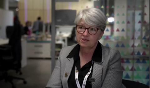 Anna Earnshaw with short white hair wearing a grey jacket in an office