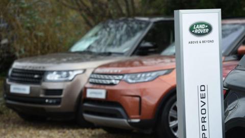 Two range rovers parked next to a sign saying Land Rover