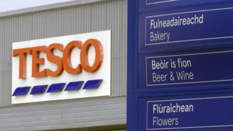 Tesco in Stornoway with Tesco sign in background and a blue sign in the foreground