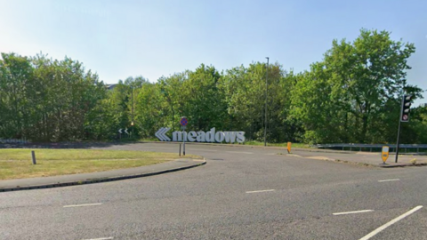 A street view of a busy road. There are trees on the side of the road.