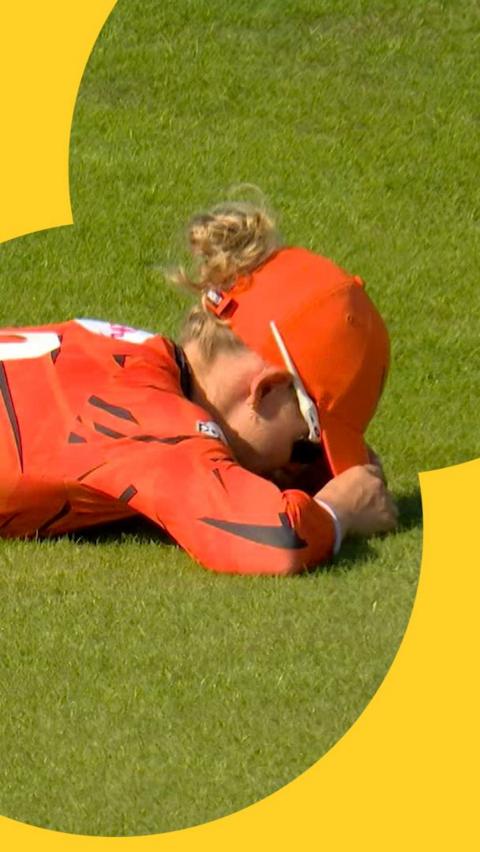 Phoebe Litchfield lies on the floor with her head buried after missing what would've been an excellent catch