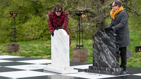 Jonathan Ross in a red wool coat and Alan Carr in a yellow scarf on a life-sized chess board in last night's episode of The Traitors.