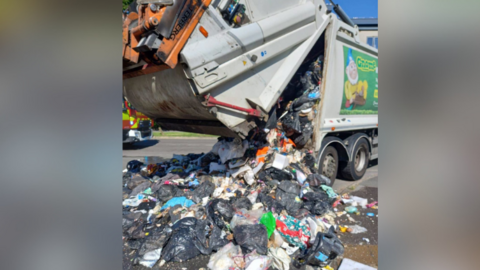 A bin lorry emptying household waste onto a Southampton street.
