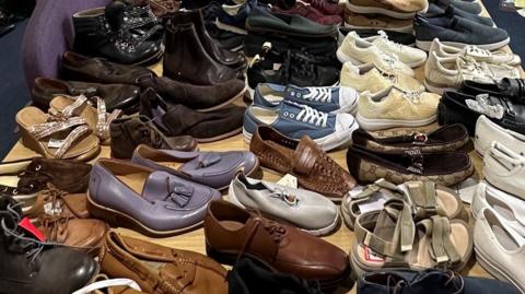 A table covered in pairs of men and womens shoes