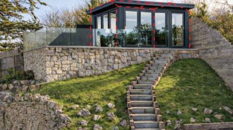 Glass cabin in a garden with a balcony surround