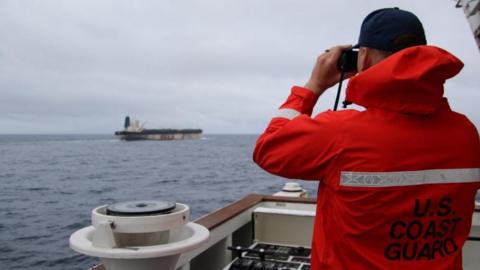 A US Coast Guard official looks through binoculars at the ship Marinera (previously known as Bella 1) in this handout image released 7 January 7 2026