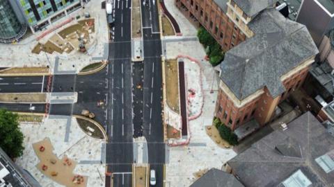 Drone shot of the junction, taken from directly overhead, showing new areas of road surface with some white lines and lots of construction barriers still in place