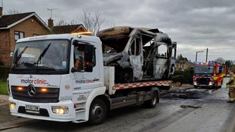 Burned-out vehicle on the back of a recovery truck