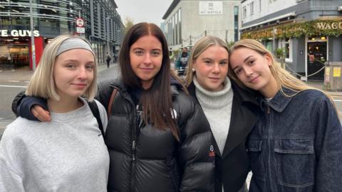 Mid shot of four young female students standing on a Brighton street looking to camera.  
From left to right - From left: Maddie Bunting, Lauren Hart, Millie Winchester, Blyth Eling, all students from the University of Brighton