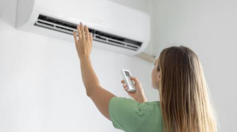 A woman switching on her air conditioning