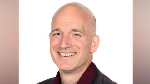 Jack Jacobs smiling as he sits for a portrait photography.