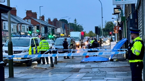 Police officers at a cordoned-off area of Narborough Road in Leicester