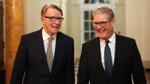 Peter Mandelson and Keir Starmer walk and laugh both wearing suits