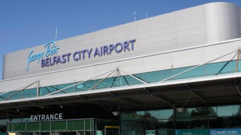 Entrance to George Best Belfast City Airport. It has a round silver roof and green-ish windows.