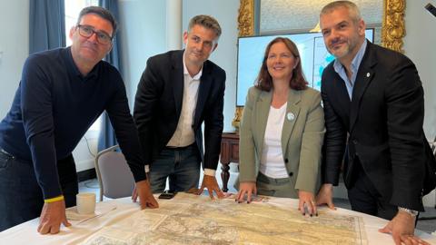 Four people gathered around a round table with a map on it of the Peak District 