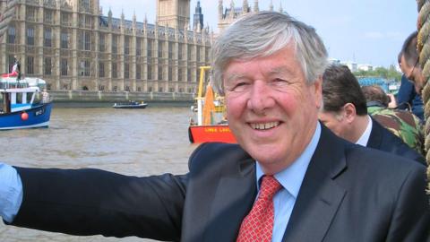 Jeffrey Titford on a boat on the Thames outside the Houses of Parliament, with other vessels in the background