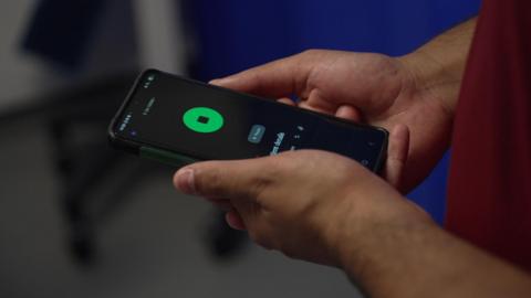 A doctor holding a mobile phone with a recording app open
