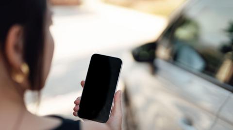 Woman holding phone near a car