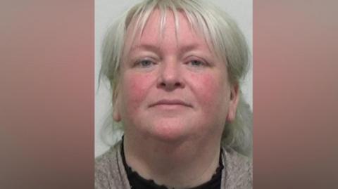 Mugshot of Thompson. She has silvery white hair tied back behind her head.